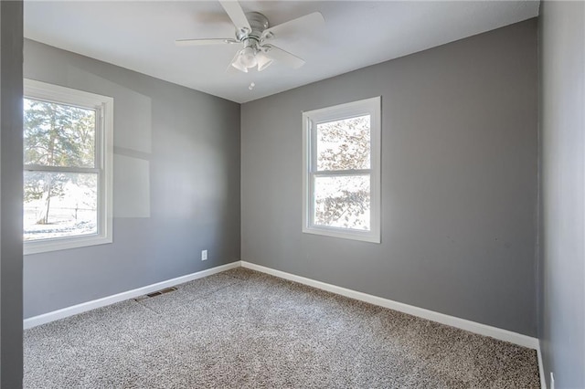 unfurnished room with baseboards, visible vents, and a healthy amount of sunlight