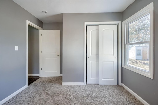 unfurnished bedroom with light carpet, a closet, and baseboards