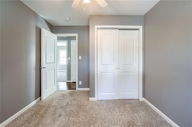 unfurnished bedroom featuring a ceiling fan, carpet, a closet, and baseboards