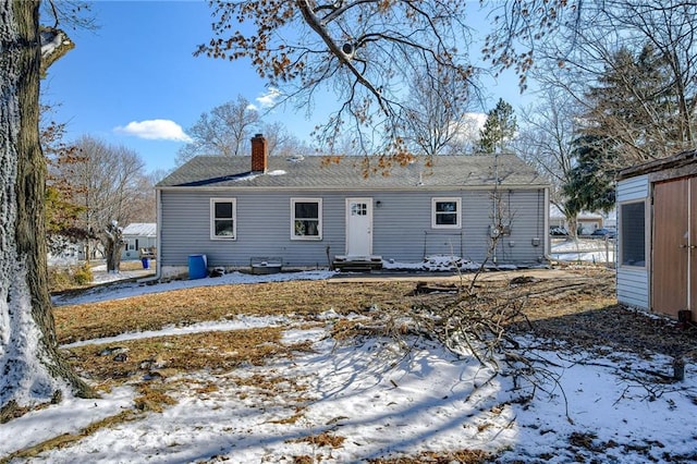 snow covered property with entry steps and a chimney