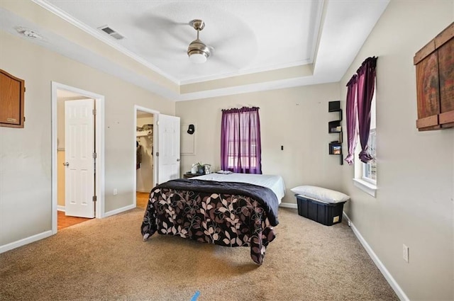 bedroom with ceiling fan, light colored carpet, ornamental molding, and a tray ceiling