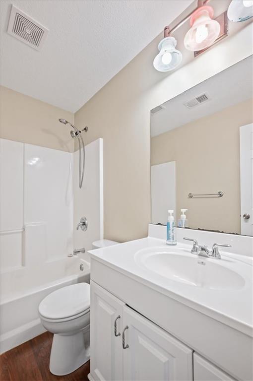 full bathroom with  shower combination, toilet, hardwood / wood-style floors, and vanity