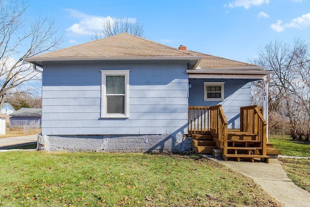 back of property with a lawn, a chimney, and a shingled roof