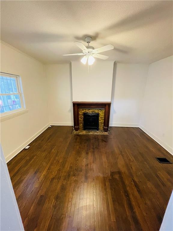 unfurnished living room featuring ceiling fan, dark wood-type flooring, and a textured ceiling