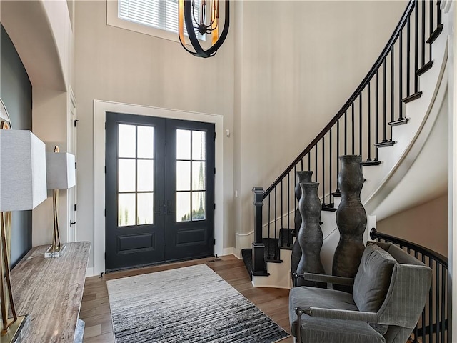 entrance foyer with hardwood / wood-style flooring, a towering ceiling, and french doors