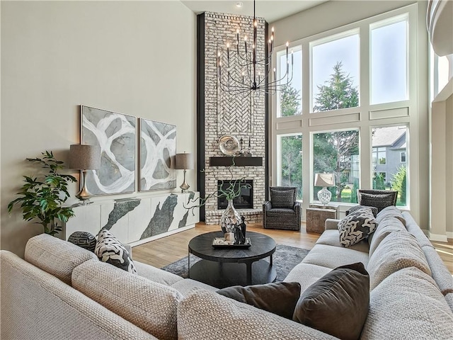 living room featuring an inviting chandelier, a towering ceiling, a fireplace, and hardwood / wood-style floors