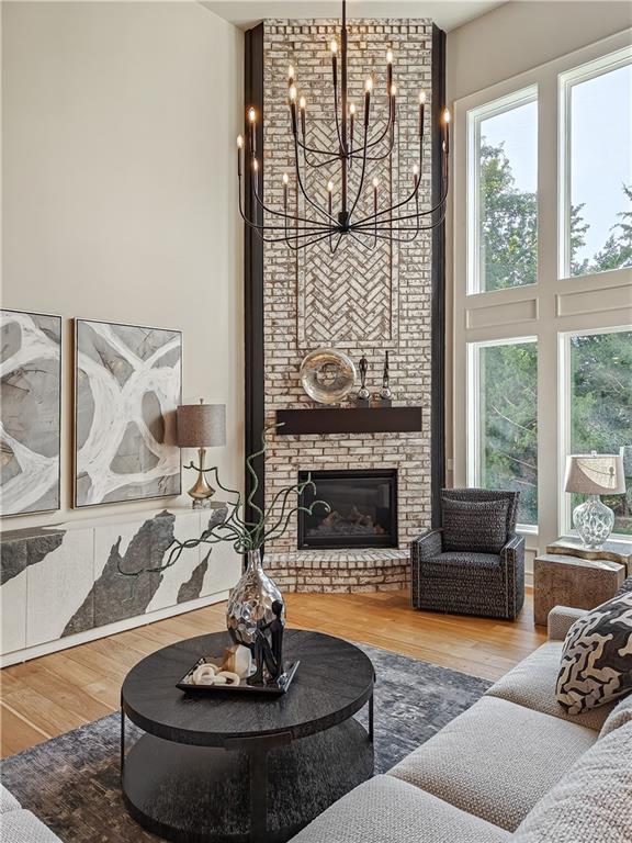 living room featuring hardwood / wood-style flooring, a healthy amount of sunlight, a fireplace, and a high ceiling