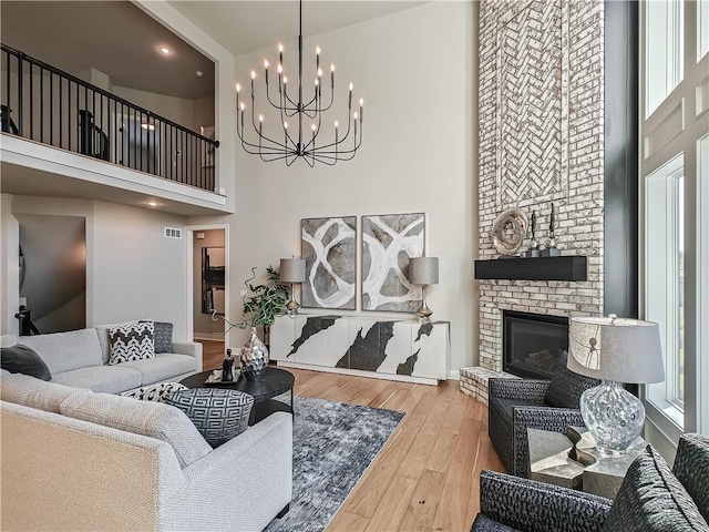 living room featuring a towering ceiling, hardwood / wood-style floors, and a brick fireplace