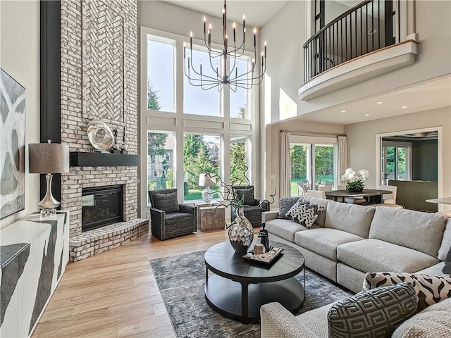 living room with an inviting chandelier, a fireplace, and light hardwood / wood-style flooring