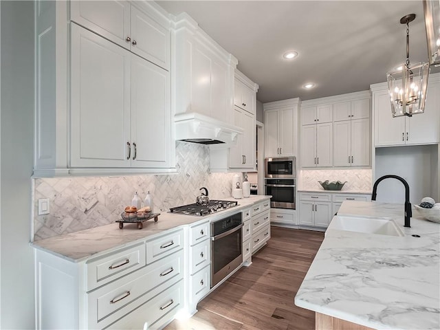 kitchen with pendant lighting, sink, appliances with stainless steel finishes, white cabinetry, and light stone counters