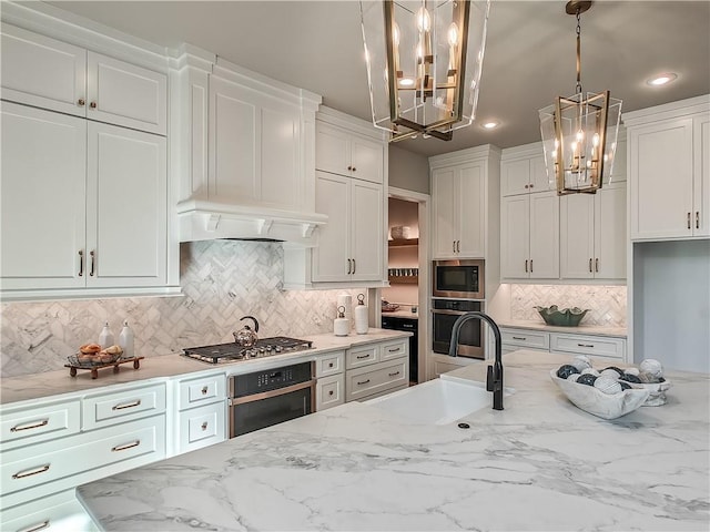 kitchen featuring sink, appliances with stainless steel finishes, white cabinets, decorative light fixtures, and a chandelier