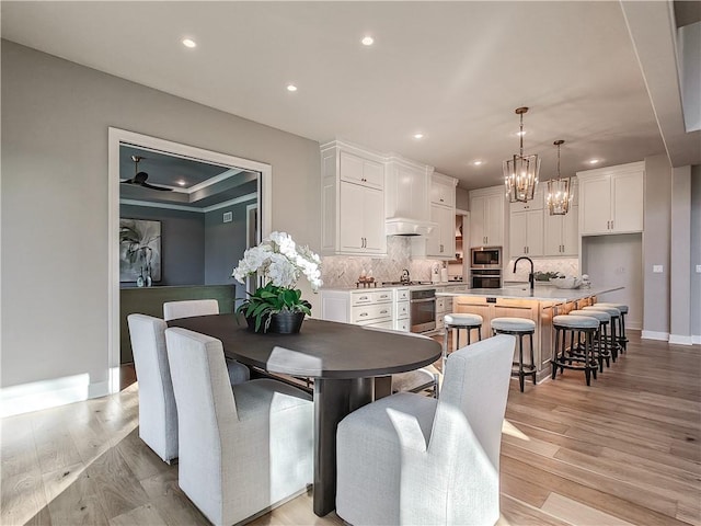 dining area featuring sink, light hardwood / wood-style flooring, and a notable chandelier