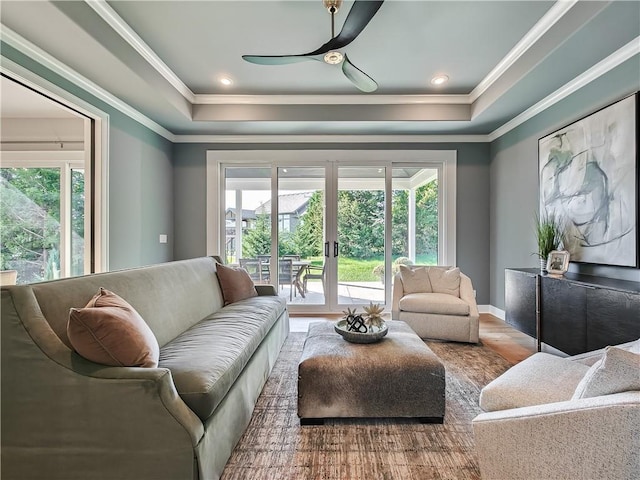 living room with wood-type flooring, ceiling fan, a tray ceiling, crown molding, and french doors