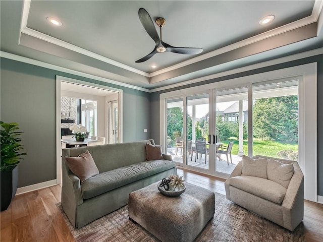 living room with crown molding, hardwood / wood-style flooring, ceiling fan, a tray ceiling, and french doors