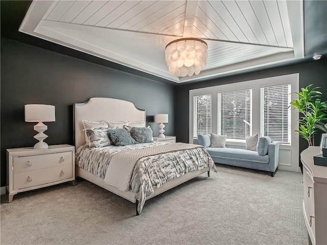 bedroom with light colored carpet and a tray ceiling