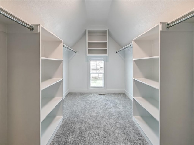 walk in closet featuring vaulted ceiling and light colored carpet