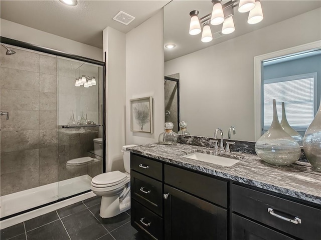 bathroom featuring tile patterned flooring, vanity, a shower with shower door, and toilet