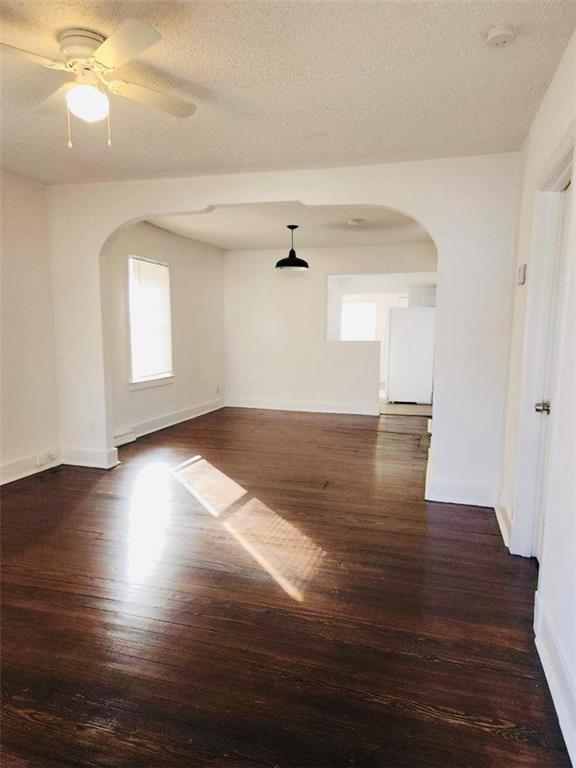 unfurnished room featuring ceiling fan, dark hardwood / wood-style flooring, and a textured ceiling