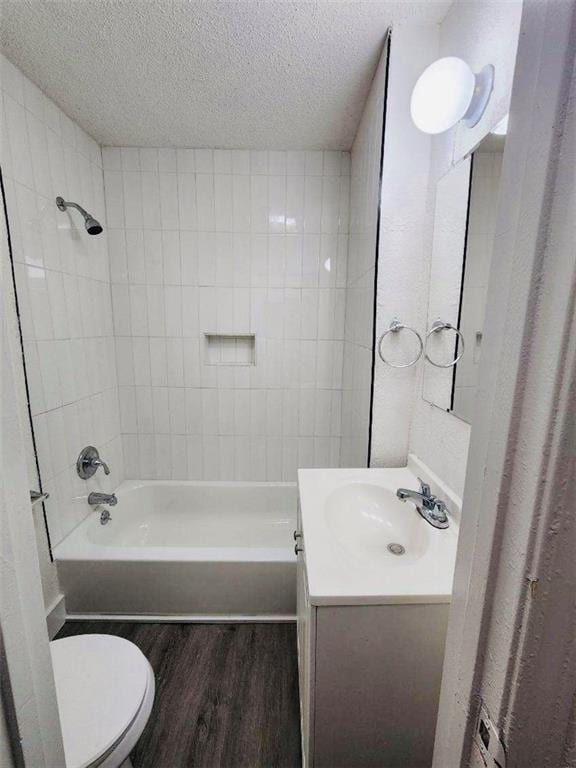 full bathroom featuring hardwood / wood-style floors, vanity, a textured ceiling, toilet, and tiled shower / bath