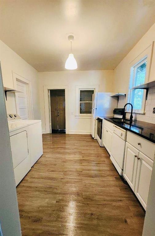 kitchen with hanging light fixtures, light wood-type flooring, dishwasher, washer and clothes dryer, and white cabinets