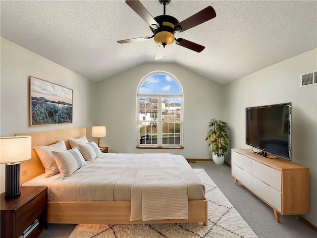 bedroom featuring ceiling fan, vaulted ceiling, light carpet, and a textured ceiling