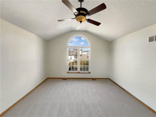 unfurnished room with ceiling fan, vaulted ceiling, a textured ceiling, and carpet flooring