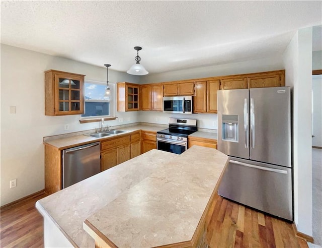 kitchen with sink, light hardwood / wood-style flooring, stainless steel appliances, a textured ceiling, and decorative light fixtures