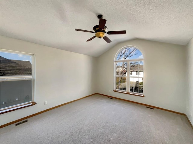 unfurnished room with ceiling fan, lofted ceiling, carpet flooring, and a textured ceiling