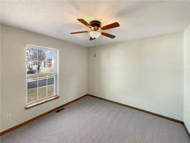 carpeted empty room with ceiling fan and a textured ceiling