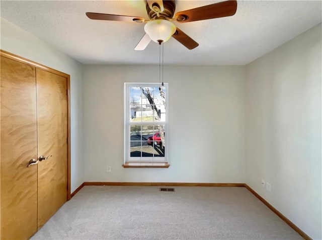 interior space featuring ceiling fan, light carpet, and a textured ceiling