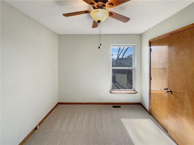 spare room featuring ceiling fan, light colored carpet, and a textured ceiling