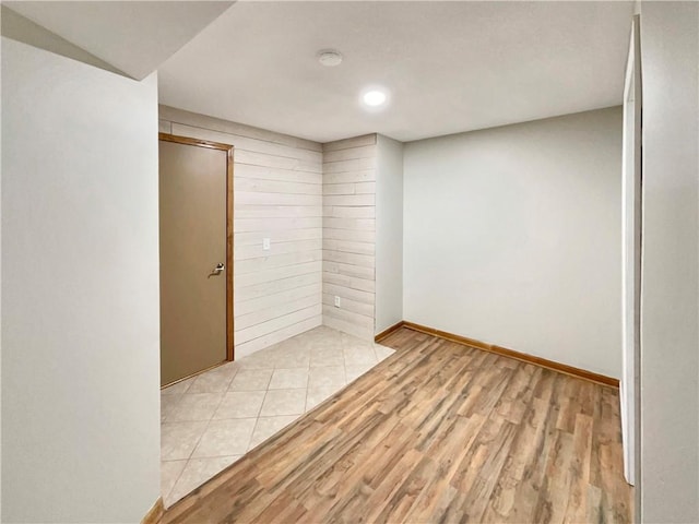 unfurnished room with light hardwood / wood-style flooring and wood walls