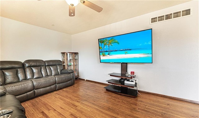 living area featuring a ceiling fan, visible vents, baseboards, and wood finished floors