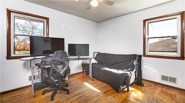 office space with visible vents, ceiling fan, baseboards, and wood finished floors