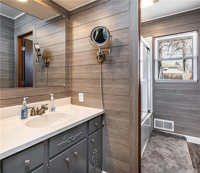 full bath featuring baseboards, wooden walls, visible vents, and vanity