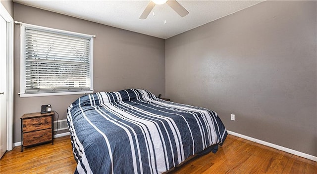 bedroom featuring ceiling fan, wood finished floors, visible vents, and baseboards