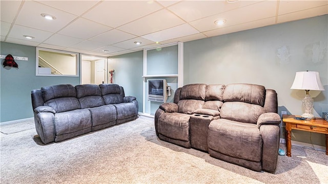 living room with heating unit, a paneled ceiling, and light colored carpet