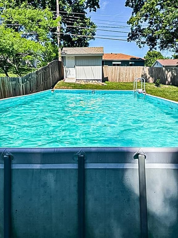 view of swimming pool with a fenced backyard, a storage unit, a fenced in pool, and an outbuilding