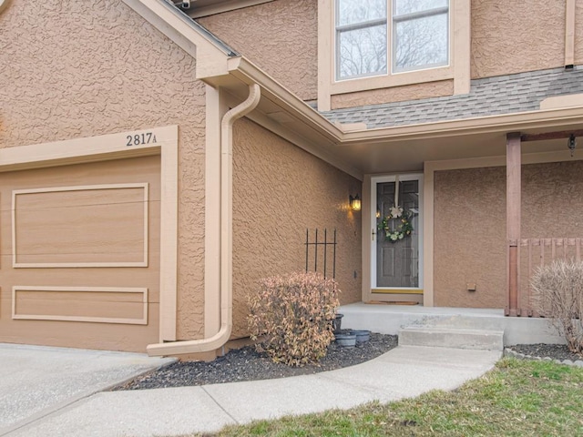 property entrance featuring a garage, roof with shingles, and stucco siding