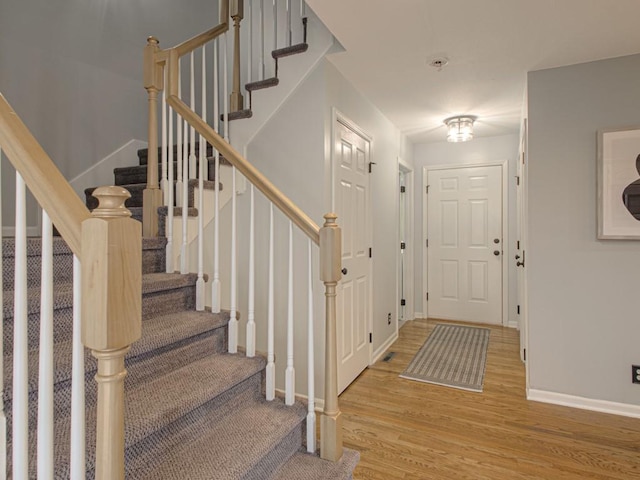 foyer featuring light wood-style flooring, stairs, and baseboards