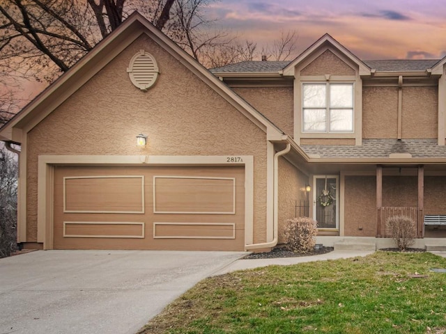 view of front of home featuring an attached garage, covered porch, a shingled roof, concrete driveway, and stucco siding