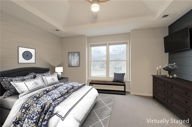 bedroom with light carpet, ceiling fan, visible vents, and a raised ceiling