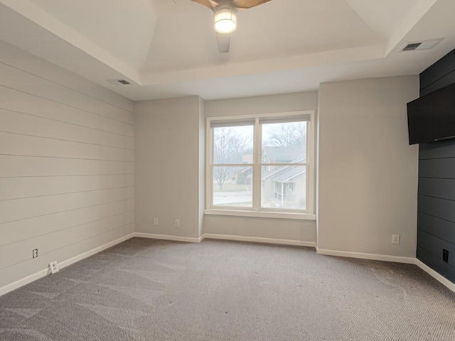 spare room with baseboards, a raised ceiling, and carpet flooring