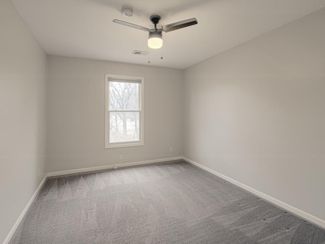 carpeted empty room with baseboards, visible vents, and a ceiling fan