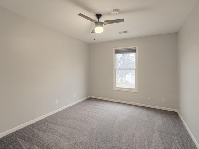 carpeted empty room with baseboards, visible vents, and a ceiling fan