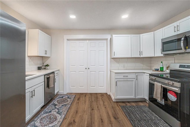 kitchen featuring stainless steel appliances, white cabinets, dark hardwood / wood-style flooring, and decorative backsplash