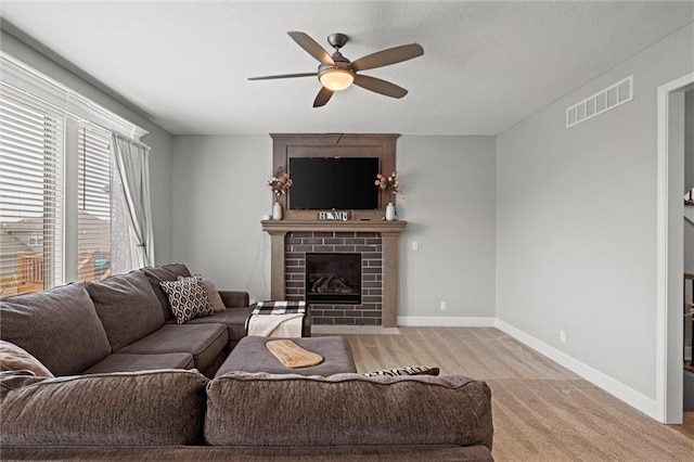 carpeted living room featuring ceiling fan and a large fireplace