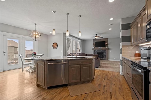 kitchen with a brick fireplace, appliances with stainless steel finishes, sink, a kitchen island, and dark brown cabinets