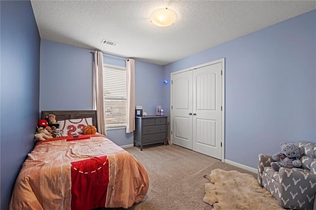 bedroom with a closet, light carpet, and a textured ceiling