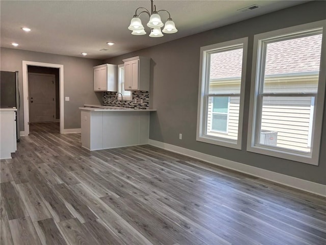 4909 S Creek Woods Dr, Saint Joseph, MO 64507 - kitchen featuring a chandelier, white cabinetry, backsplash, wood finished floors, and a peninsula